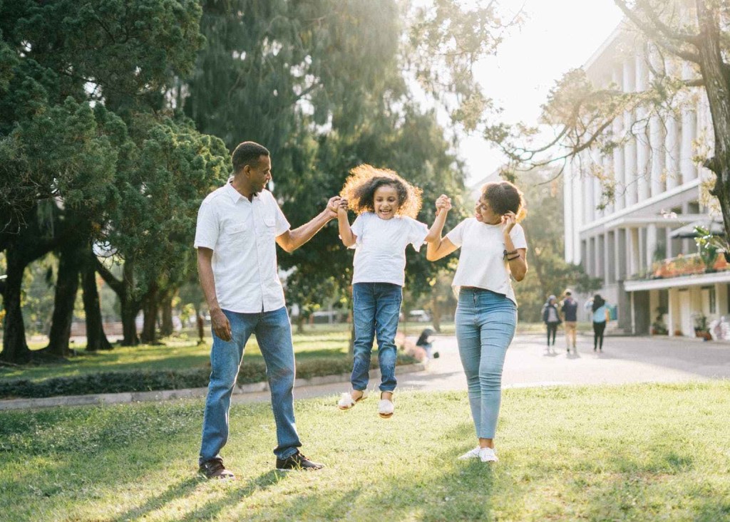 a man and a woman assisting a girl while jumping